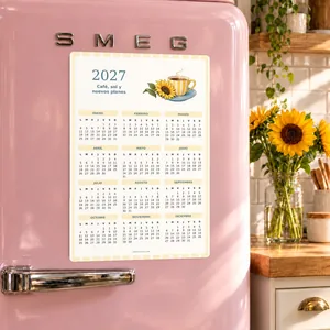Calendario imantado 2027 Café, sol y nuevos planes sobre una nevera rosa en una cocina con girasoles.