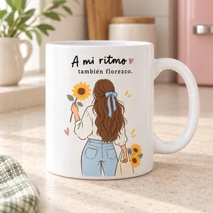 Taza A mi ritmo también florezco. La ilustración de una chica de espaldas y las flores acompaña una frase sobre respetar tu propio ritmo.