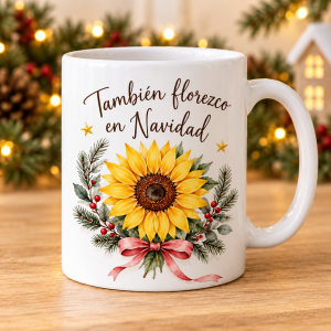Taza blanca con la frase También florezco en Navidad, girasol amarillo, ramas verdes, frutos rojos y lazo rosa.