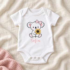 Body bebé Koala con nombre. Un koala con girasol y lazo rosa acompaña el nombre en rosa palo.