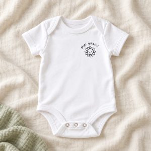 Body bebé Mini girasol. Un pequeño emblema de girasol y texto negro quedan en el pecho.